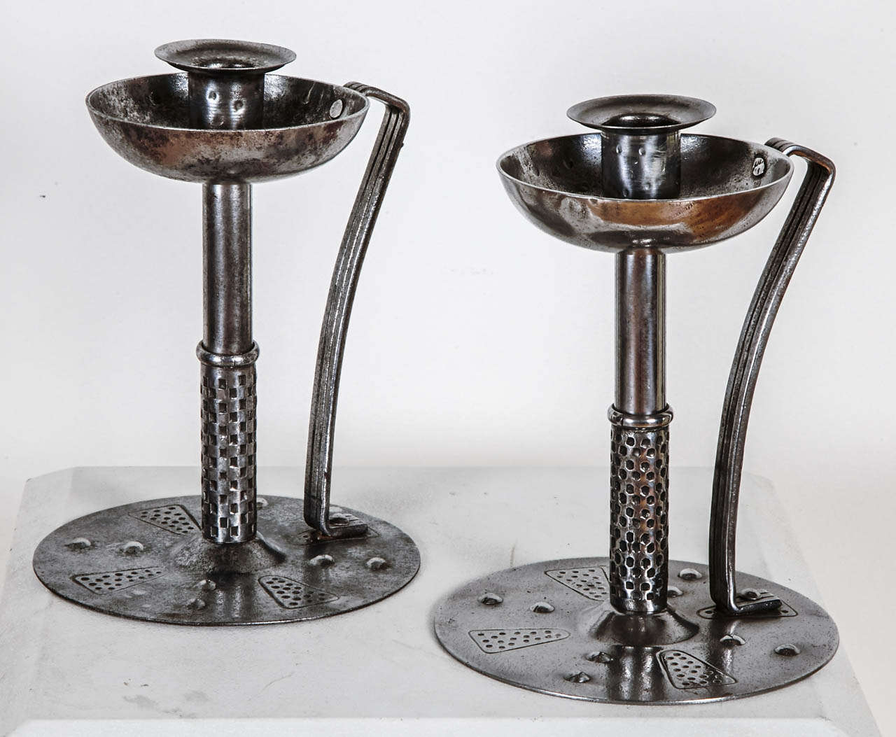 Pair of grey patinated steel candlesticks with a circular base and a geometrically carved trunk. Stamp signature under the base. By Hugo Berger (aka Goberg). From Germany Jugentstil/Arts and craft, circa 1910. Stamp under the base.