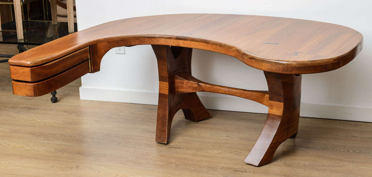 Unique and large sculpted from stacks of laminated walnut desk. Spectacular biomorphic design form with curved apron, two drawers, butterfly joints details.
One of a kind desk in the manner of Wendell Castle, USA, 1960s.