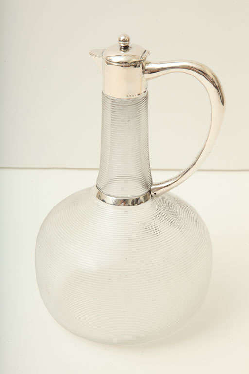 A lovely German silver mounted claret jug dating from the late 1890's. Ribbed glass makes up the base of this beautifully shaped piece. Stamped with Germany's trademark the crescent and the crown, 800 for German silver, and maker's mark 