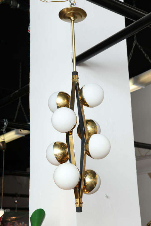Exciting eight-light chandelier made in 1955 in Milan by Stilnovo.
Eight white cased glass shades on a brass and steel stem.
Great form. Beautiful quality.
  