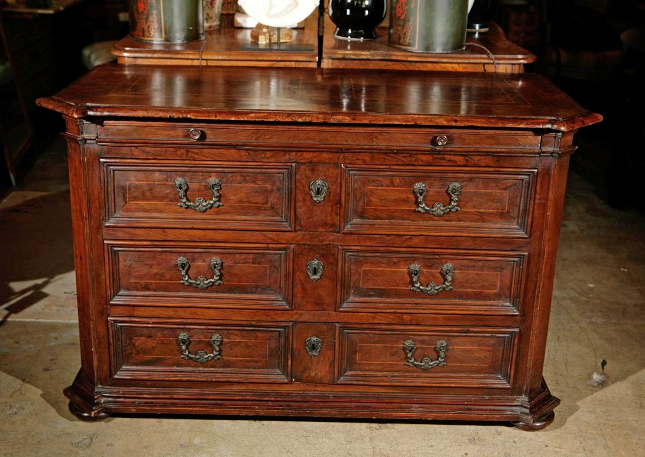 A large, 19th c., hand-carved, walnut, clipped-corner commode. The slim drawer above the solid wood tops, surmounts three large drawers, each with mitered corner paneling. The whole on bun feet.  Cast bronze mounts.
