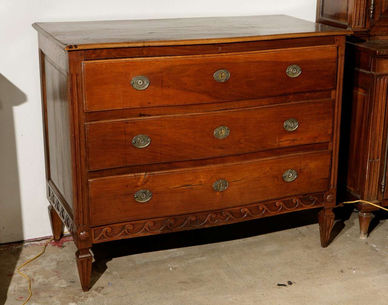 Three drawer, walnut commode with bronze hardware and hand carved apron. 