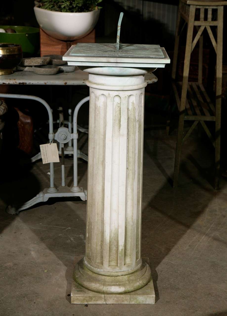 A fluted column serves as a platform to hold this detailed iron sundial inscribed with the words 
