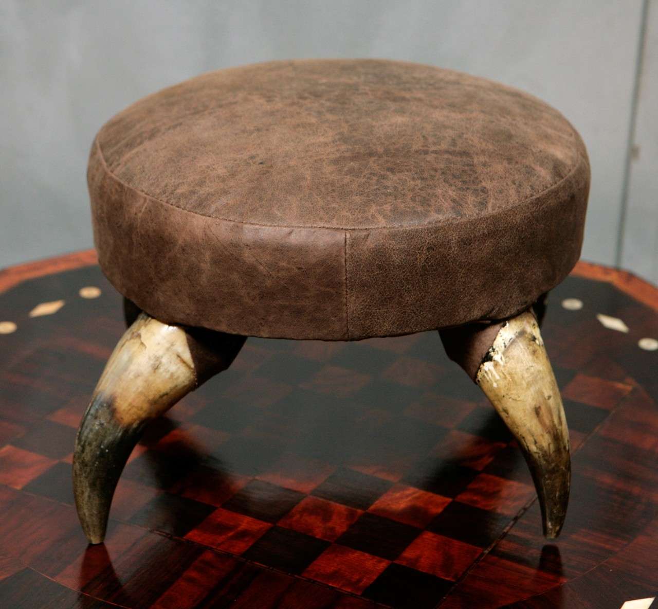 This horn stool is raised on four legs and is finished in a brown upholstery. It is circa 1880 - 1910, American and will work well in most settings. 