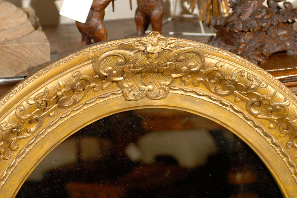 19th Century English 1870s Oval Giltwood Carved Mirror with Floral Arabesques and Small Crest For Sale
