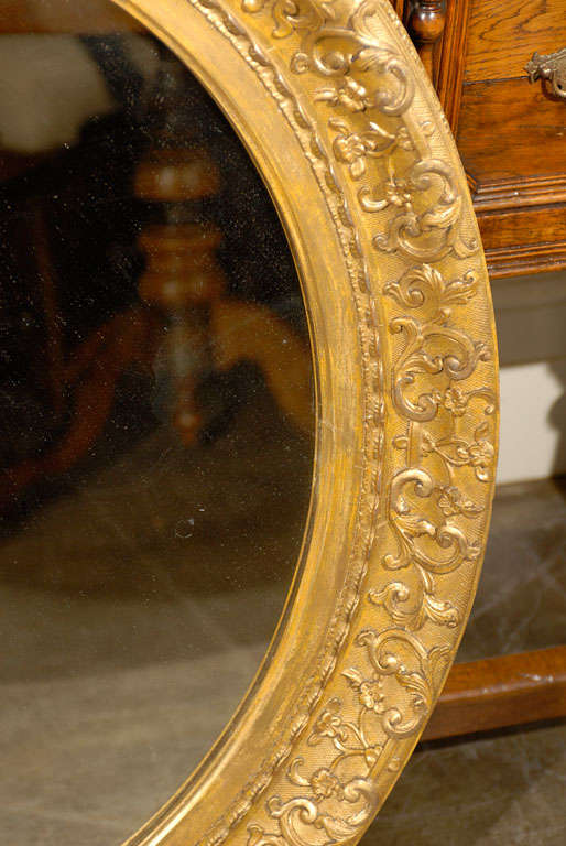 English 1870s Oval Giltwood Carved Mirror with Floral Arabesques and Small Crest For Sale 1