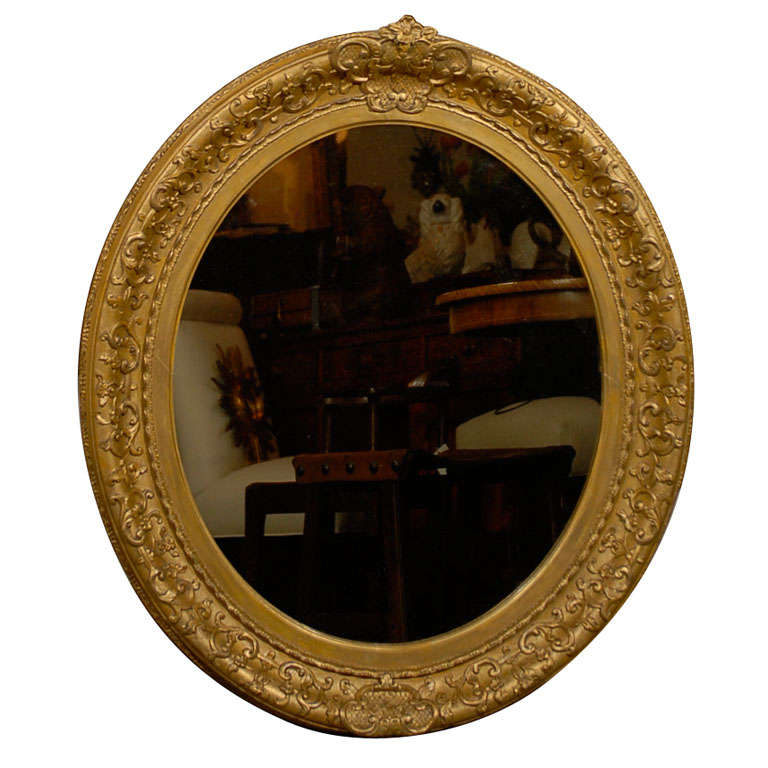 Miroir ovale anglais des années 1870 en bois doré sculpté avec arabesques florales et petite crête