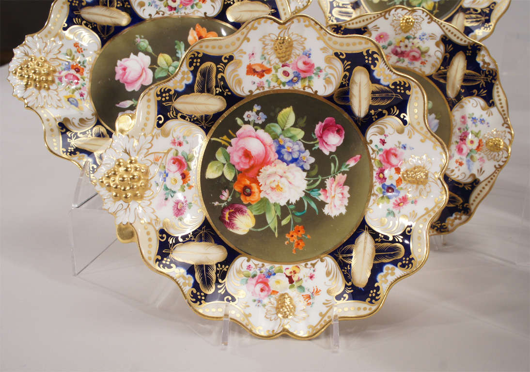 This extensive and complete dessert service has 12 dessert plates (8" diameter) a lovely oval footed compote ( 6" tall, 2 oval serving bowls and 2 shell-shaped serving bowls. Each piece is uniquely painted with a central botanical bouquet