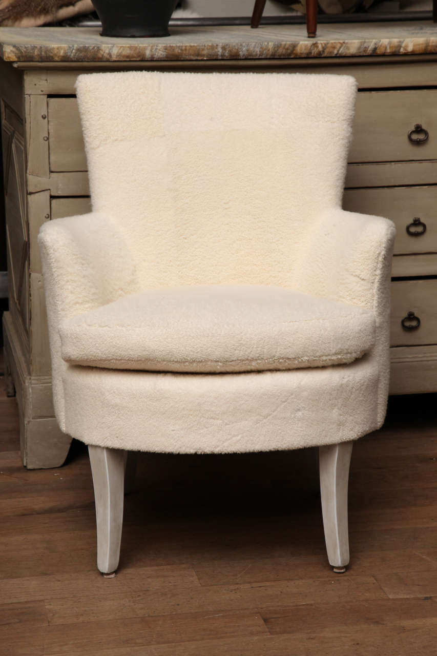 A diminutive wing chair circa 1950 upholstered in shearling patchwork with transparent whitewash finished legs.