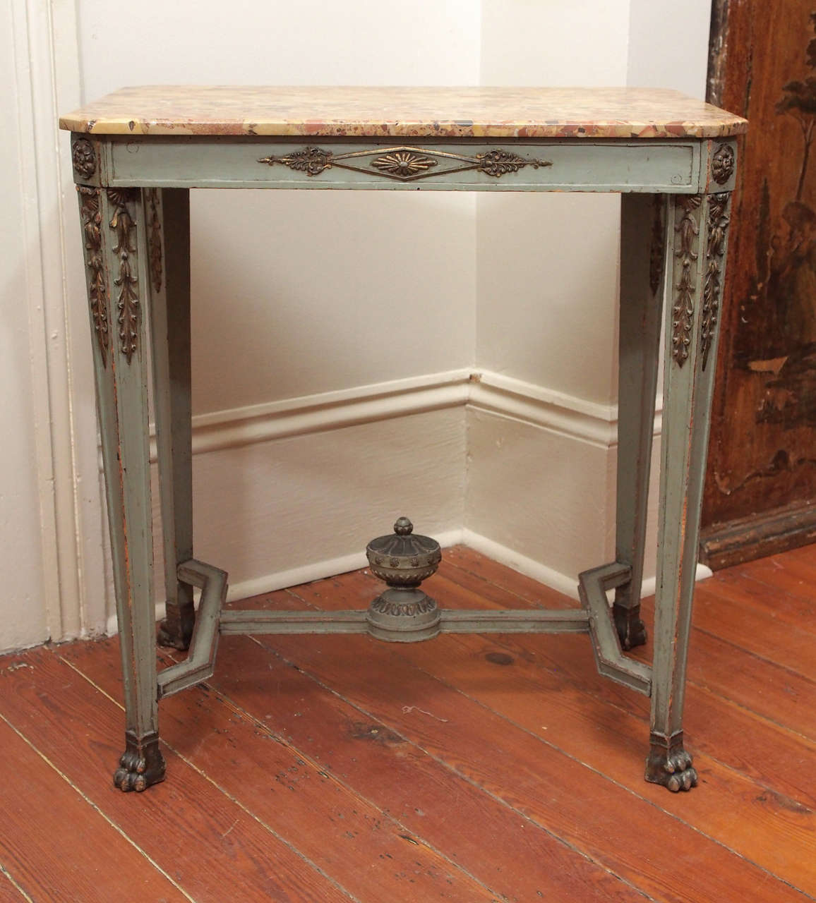 A polychrome French Empire table with molded, tapered legs ending in paw feet, the legs joined by an 