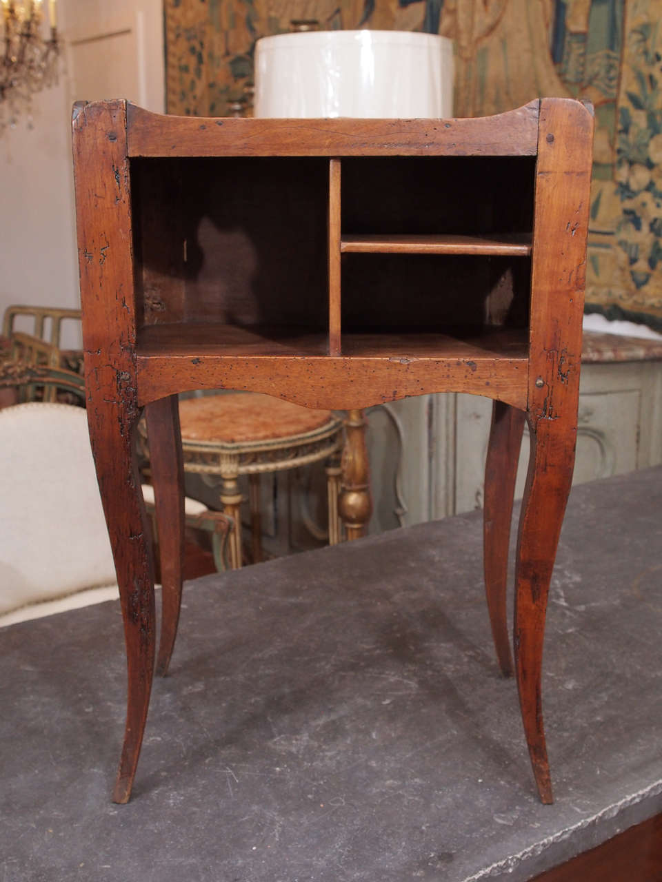 A charming French, walnut nightstand with cabriole legs and a scalloped apron and gallery, the table sides pierced with a stylized clover, and the interior with cubby holes.