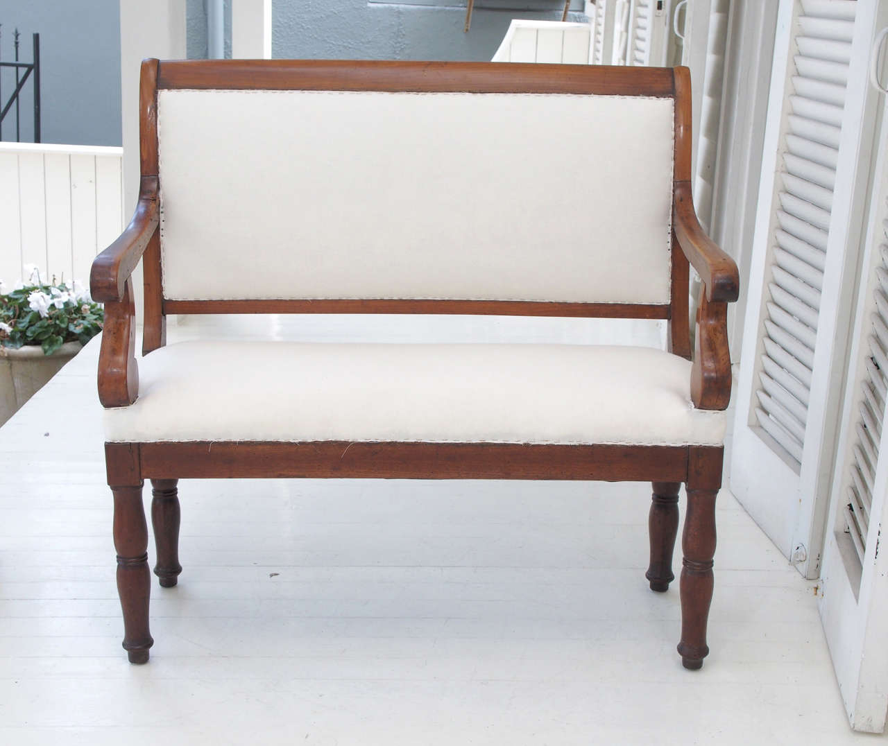 A settee, with a scrolling back, open arms and simple, turned legs. Ready to go: recently upholstered and covered in muslin.