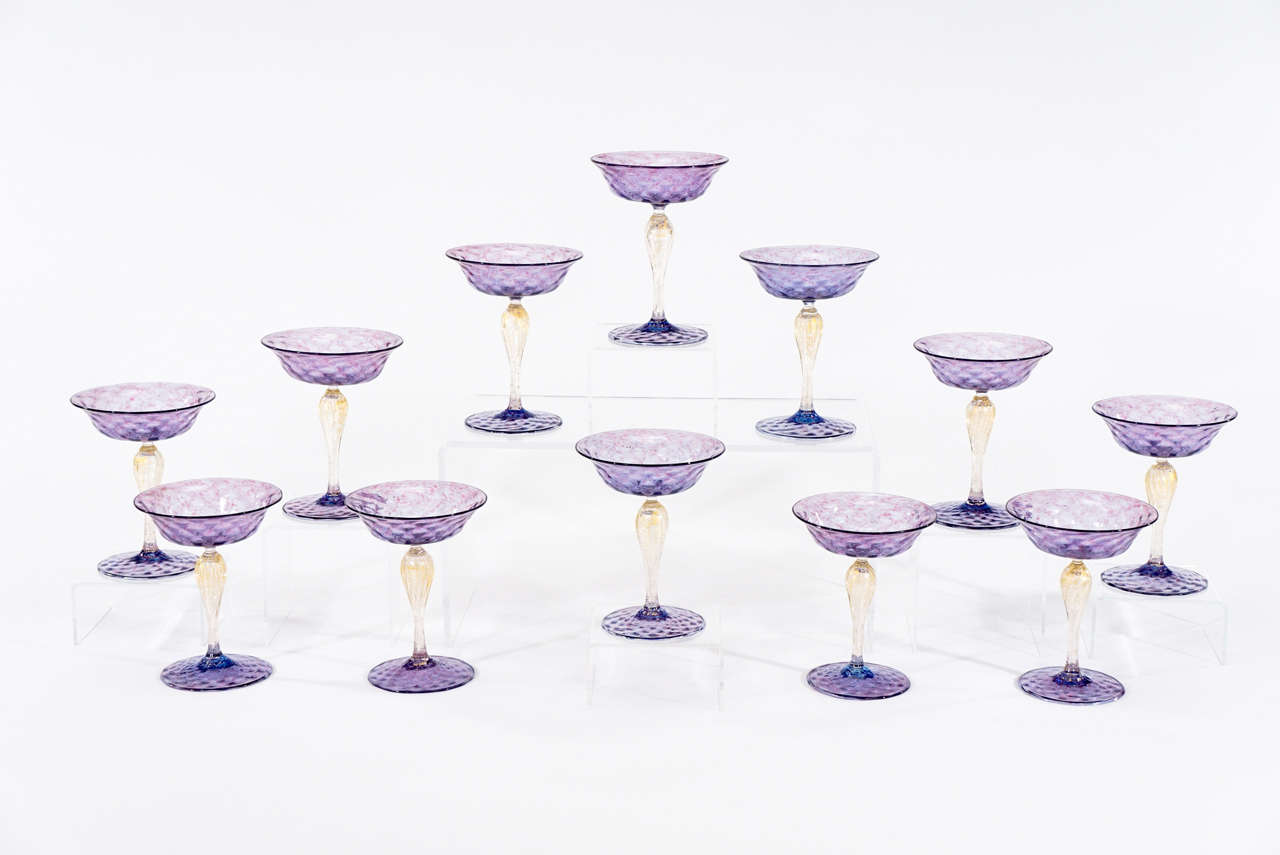 This is a beautiful set of 12 handblown goblets made by Salviati, circa 1920s. The lavender or amethyst bowl and foot has a quilted optic pattern with subtle raspberry pink inclusions and the stem is tall and elegant clear glass highlighted with