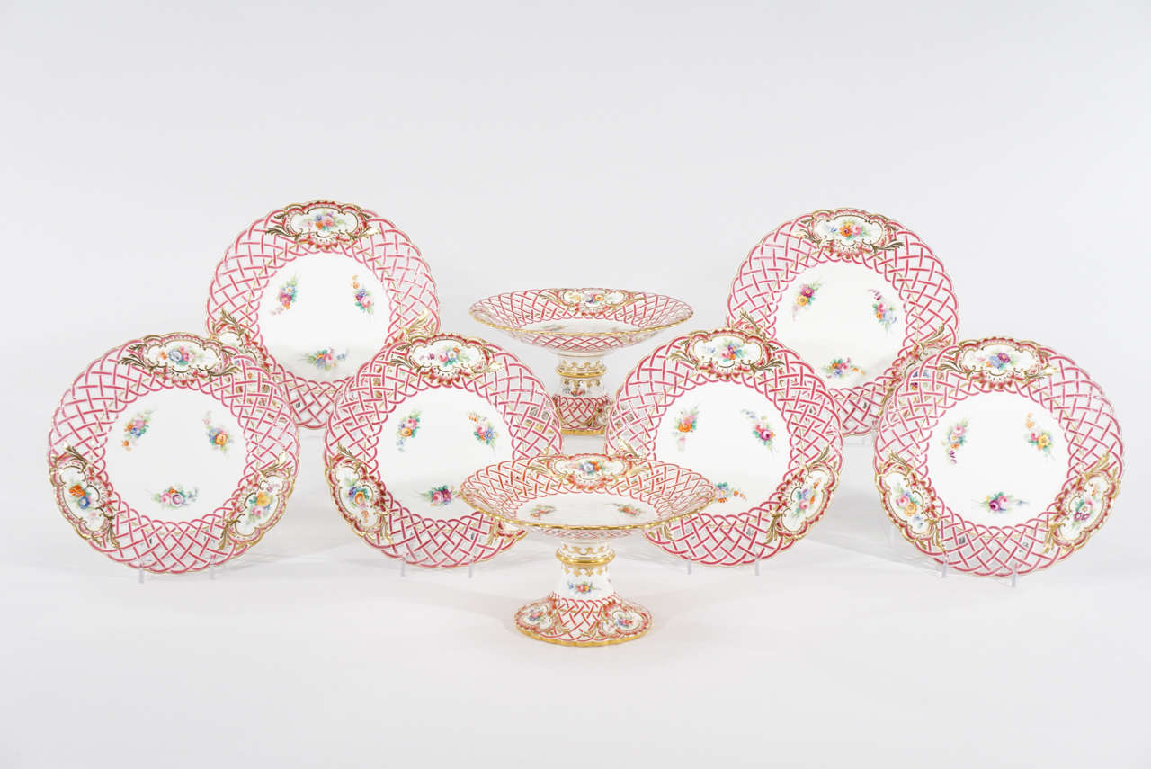 This is a lovely grouping of 19th century Minton pierced rim hand-painted dessert plates with a pair of tall matching footed compotes. The bright strawberry-pink enamel basket-weave border is accented with three hand-painted floral decorated