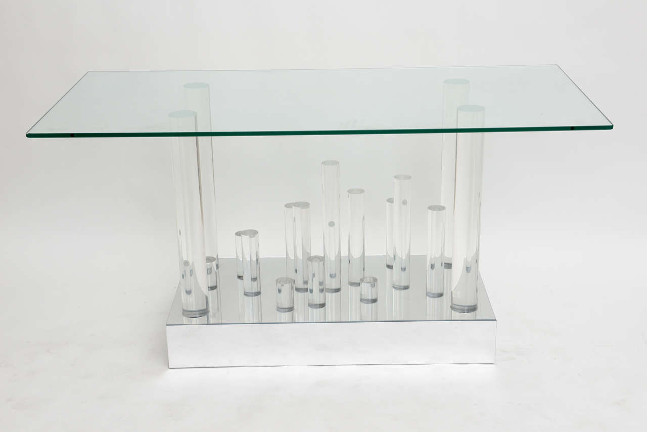 The rectangular glass top above chunky Lucite cylinders of graduated length above a base that is mirrored. Can be used as a dining table with larger glass, base only dimensions are 19 x 36