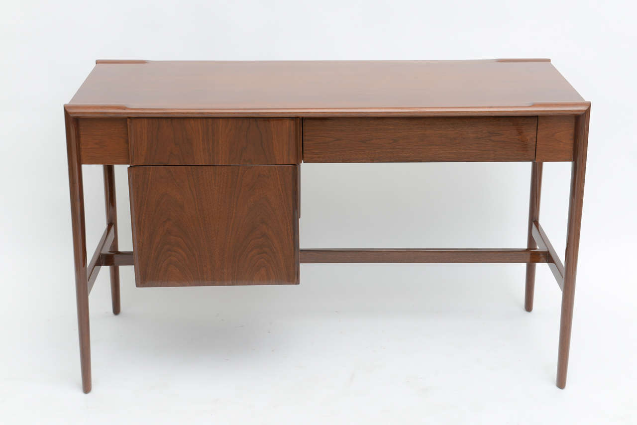The rectangular top with lip edge above a frieze with a pencil drawer with stylized edges and a large file drawer with similar details, on round tapering legs with a cross stretcher.