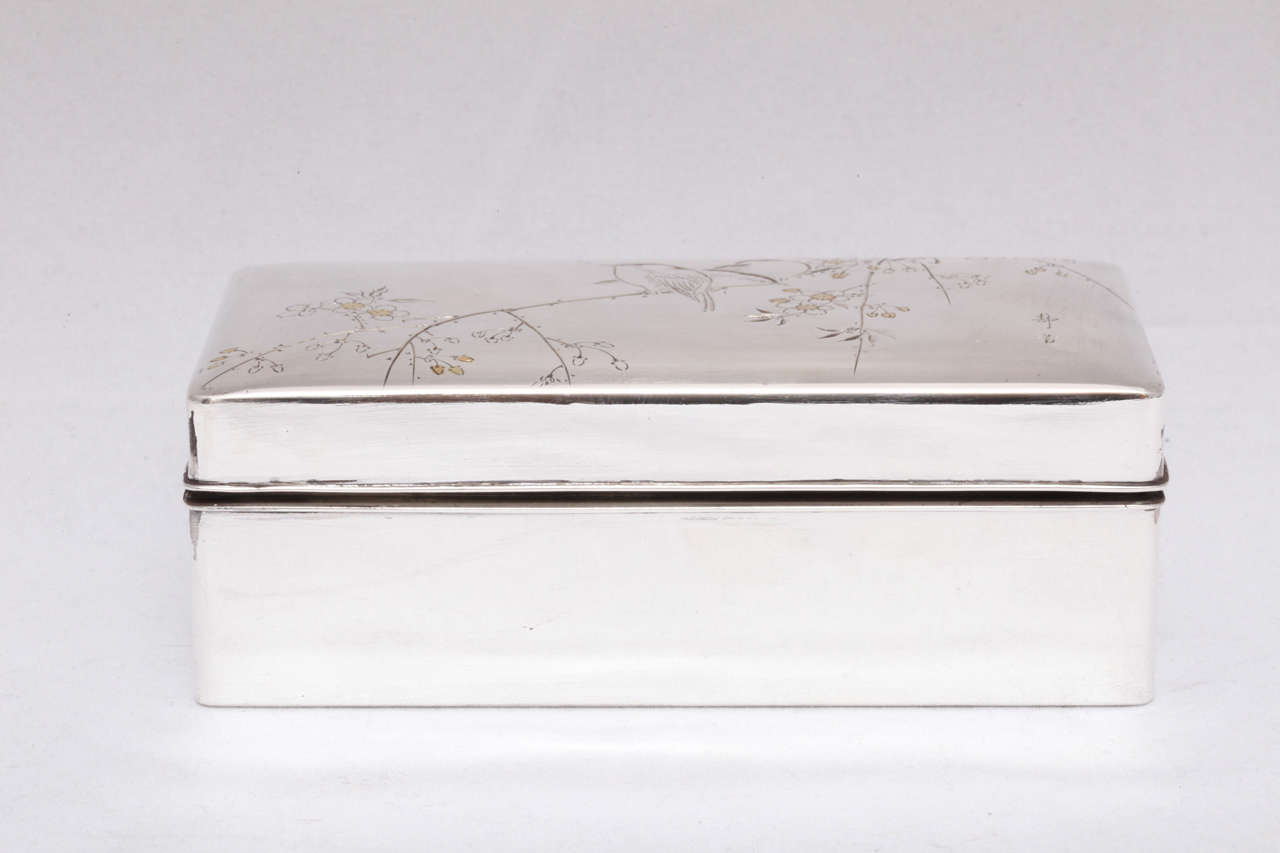 Japanese, Meiji period sterling silver and gold (mixed metals) hinged table box, Japan, circa 1900. Beautifully etched with birds, branches and flowers. The centre of each flower and some of the leaves are inlaid with gold. Measures: 4 3/4"
