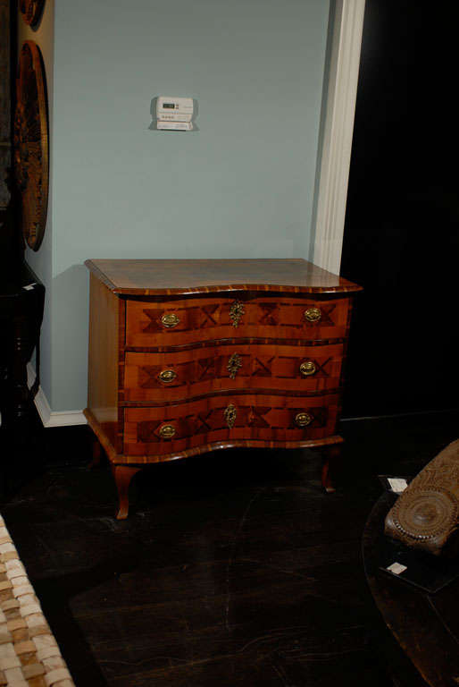 A European period Rococo three-drawer chest. This 18th century Rococo chest of drawers features a serpentine front with nice marquetry details on each drawer, including x-shaped motifs. The hardware is made of ring pulls and Rococo shaped