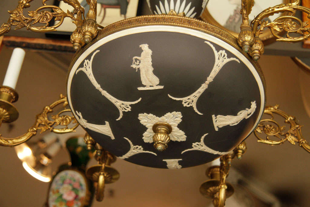 A Wedgwood Jasperware black and white chandelier. The circular shaft, centered by an Etruscan vase, is connected to an inverted disc decorated with a relief of classical figures. The upturned arms of the chandelier terminate in circular drip pans