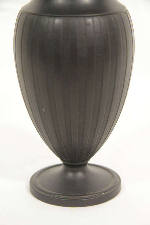 A pair of Wedgwood Black Basalt small vases of neoclassical design. They were engine turned on a lathe to achieve their precisely grooved vertical columns.<br />
Black Basalt was created by Josiah Wedgwood in the 18th century. Wedgwood transformed