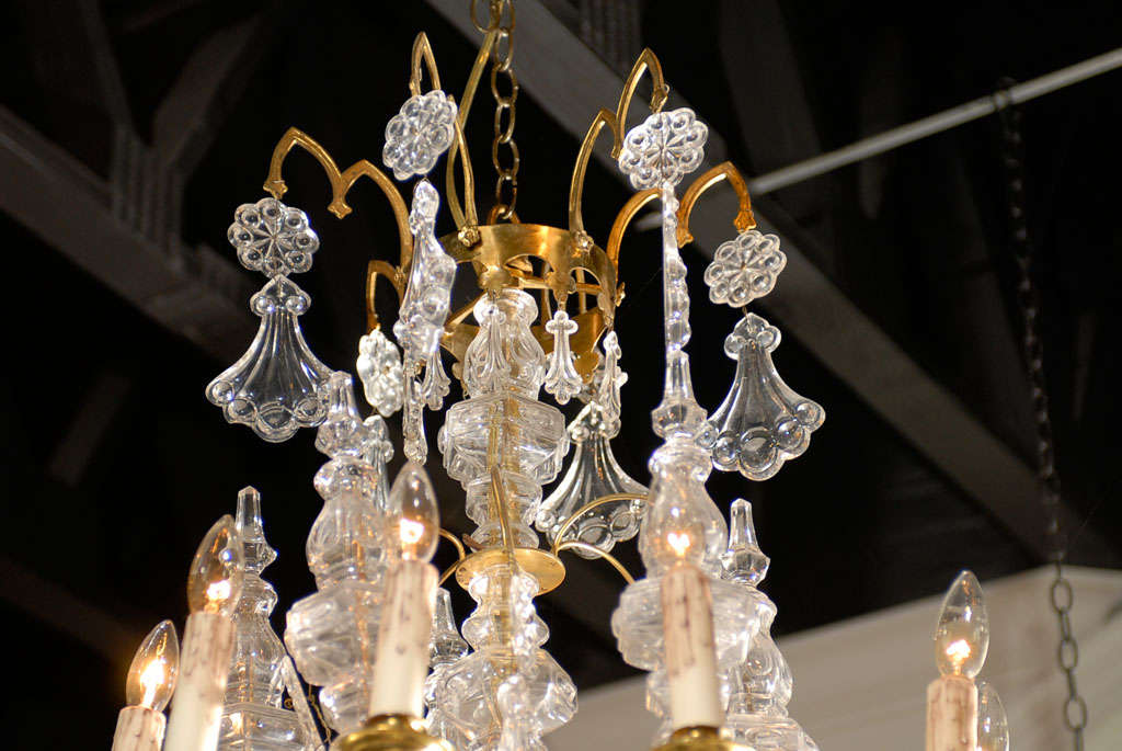 Lampadario francese a 10 luci in cristallo e ottone dell'inizio del XX secolo, con cristalli pendeloque ornati. Nato nei primi anni del XX secolo durante l'epoca della Belle Époque, questo lampadario francese è caratterizzato da un'armatura in