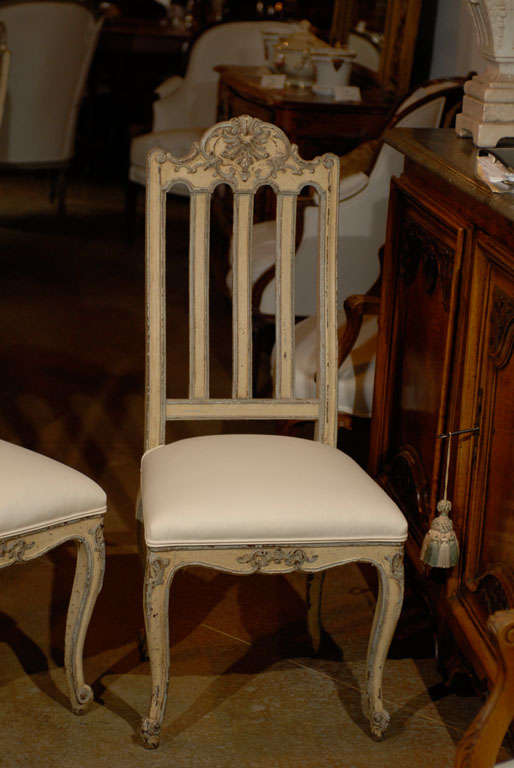 A set of six Belgian Rococo style dining room side chairs from the mid-19th century with carved crests and new upholstery. Each of this set of Belgian side chairs features a lathed back, surmounted by an exquisite carved crest, adorned with Rocaille