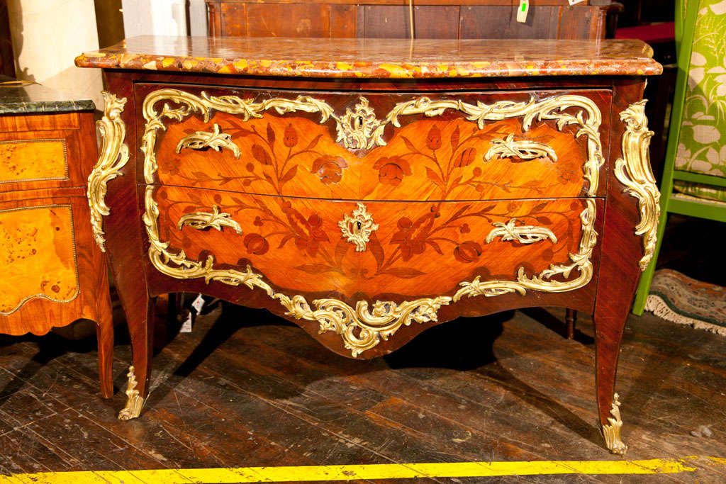 A French Regency Kingwood-veneered serpentine commode with bronze <br />
mounts, parquetry drawers with elaborate bronze handles,bombe sides inlaid with parquetry on cabriole legs.