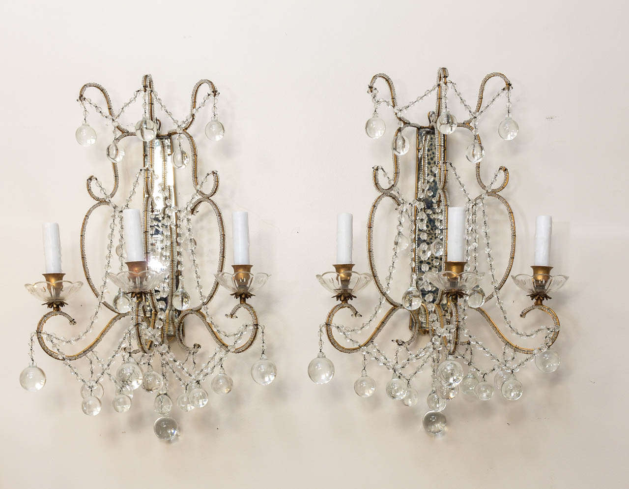 Exquisite pair of beaded crystal sconces with gilded metal frames, mirrored back plates and crystal ball drops.