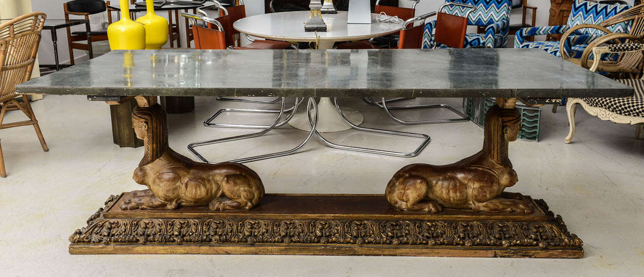 Long  and dramatic Empire style rectangular table featuring female sphinx figures with gilt headdresses,a carved acanthus leaf plinth and hand painted faux marble finished table top.