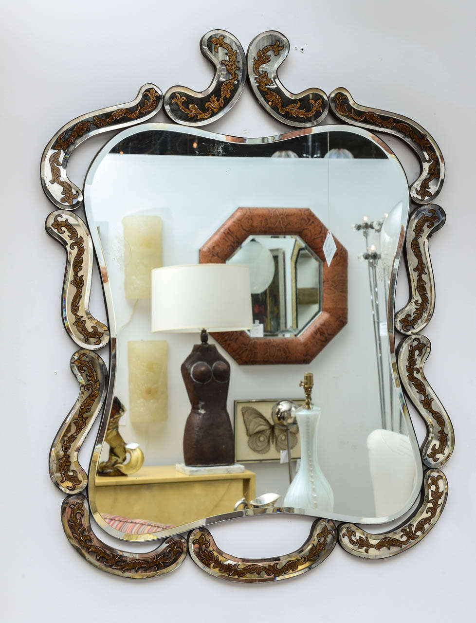 Vintage Italian reverse painted mirror with rounded corners, framed by individual scroll like pieces of mirror that contain reverse painted garlands of leaves.