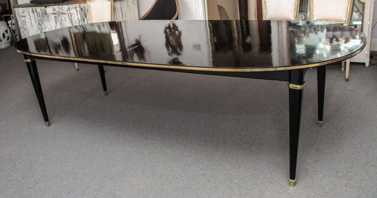 Elegant oval black lacquer dining table with brass accents; seats eight.  It is a single piece;  there are no leaves.