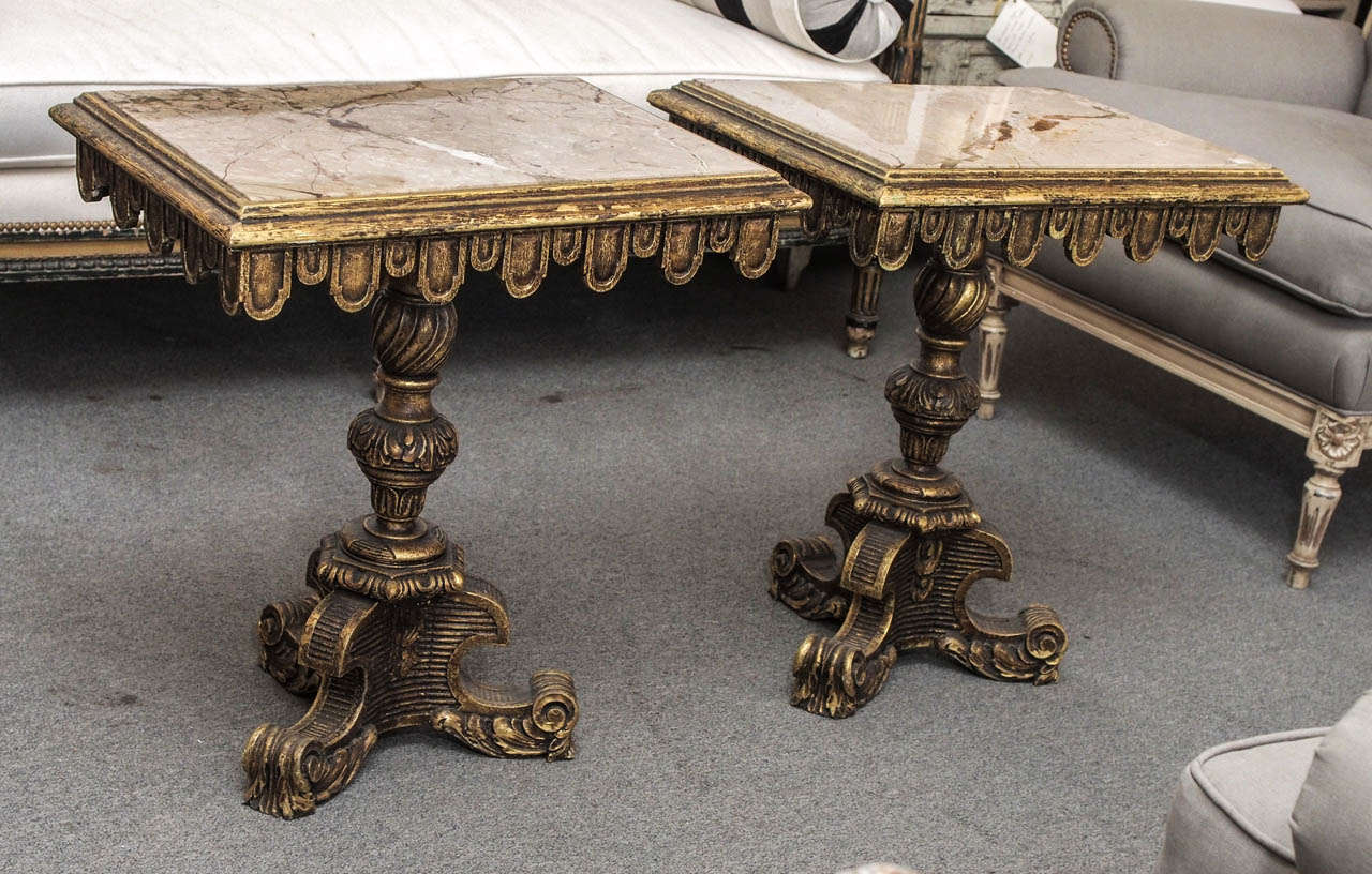 Pair of Italian side tables with carved and gilt finished  wooden bases and marble tops.  The marble is a pinkish beige with veins of cream and rust. 
.