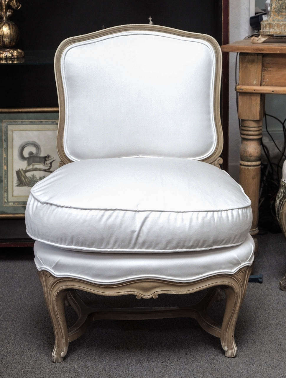 Pair of carved, painted French slipperchairs in the Jansen style;  the upholstery has been replaced. The backs and seats are upholstered and each has a separate seat cushion.