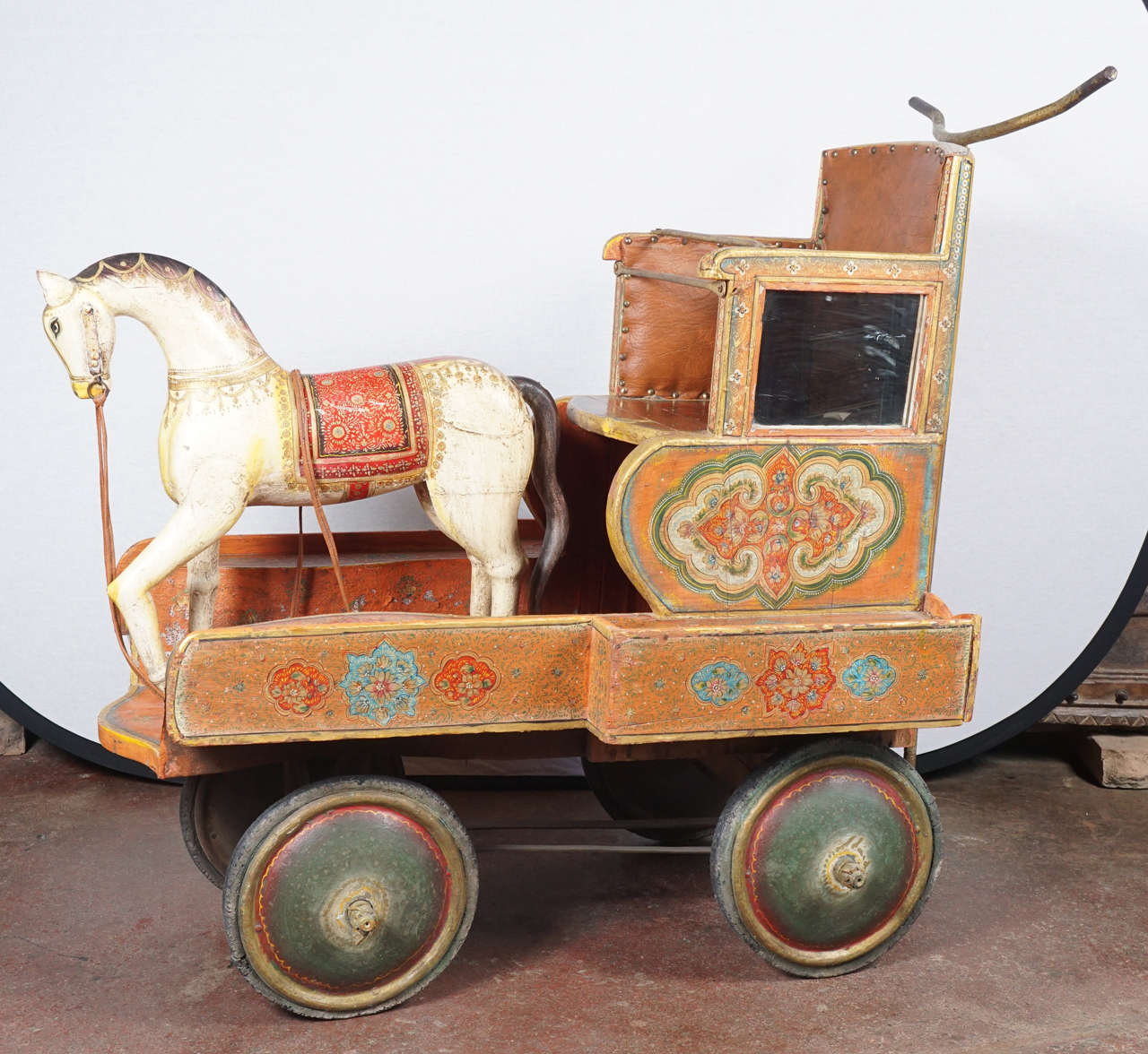 Magnificently hand-carved and hand-painted in a traditional Indian floral design, this unique piece will be a great addition as a sculptural design within an Interior space. Wheels and mechanisms are in function. Upholstery in brown leather and