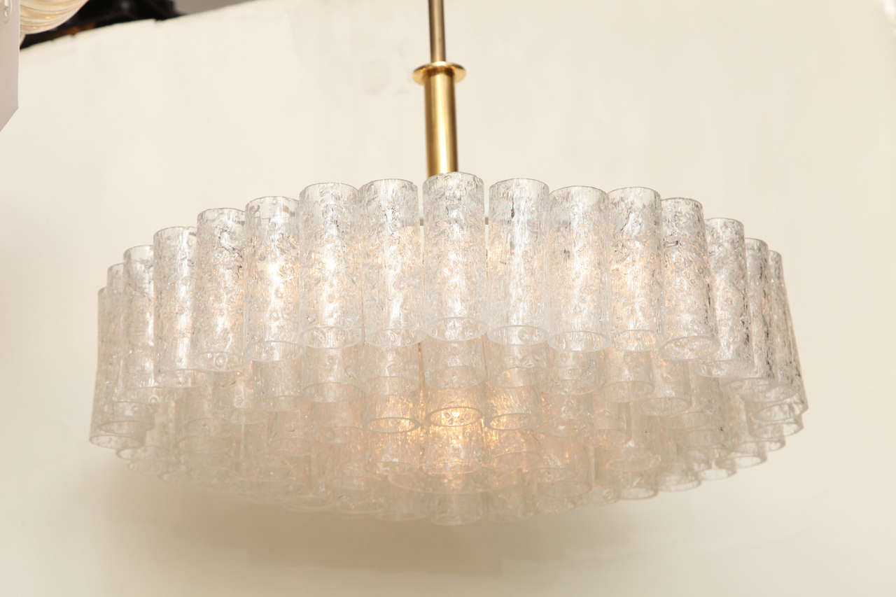 A Northern European contemporary design ceiling fixture with rings of cylindrical textured glass elements concealing electric light sockets, suspended from brass stem and canopy.