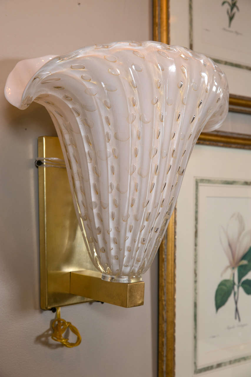A pair of fabulous Murano Hollywood Regency draper style plume form sconces. The ivory glass is decorated with 24-karat flecks. Both of these pieces are mounted on brass are fitted with 75 watt bulbs and appear to have new wiring.
Provenance:
