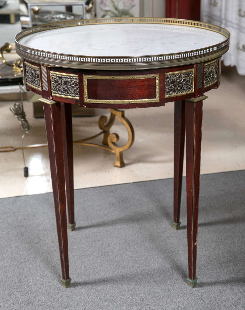 A marble-top Bouillotte table attributed to Maison Jansen. A wonderfully bronze mounted center table. The Carrara white marble top in a pierced bronze gallery supported by a single drawer apron with all-over heavy bronze mounts that terminate in