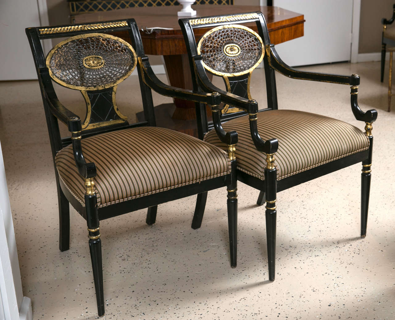Set of four ebonized gilt decorated armchairs. Can buy as little as one or as many as all four of these finely ebonized armchairs. Each tapering circular leg supporting a hi stuffed seat leading to sable armrests with spider backrests. All with a