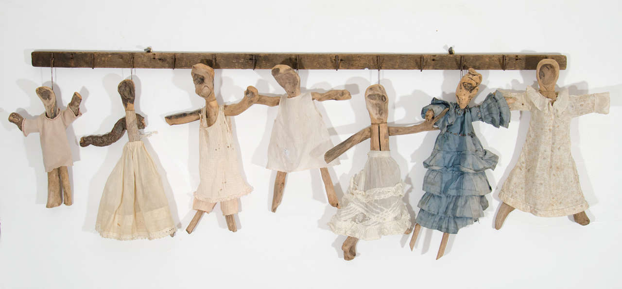 Created by a Descendant of the Mackintosh family.  Hand carved wooden dolls with vintage hand stitched fabric dresses suspended on a tobacco rack with metal hooks. 1940's.