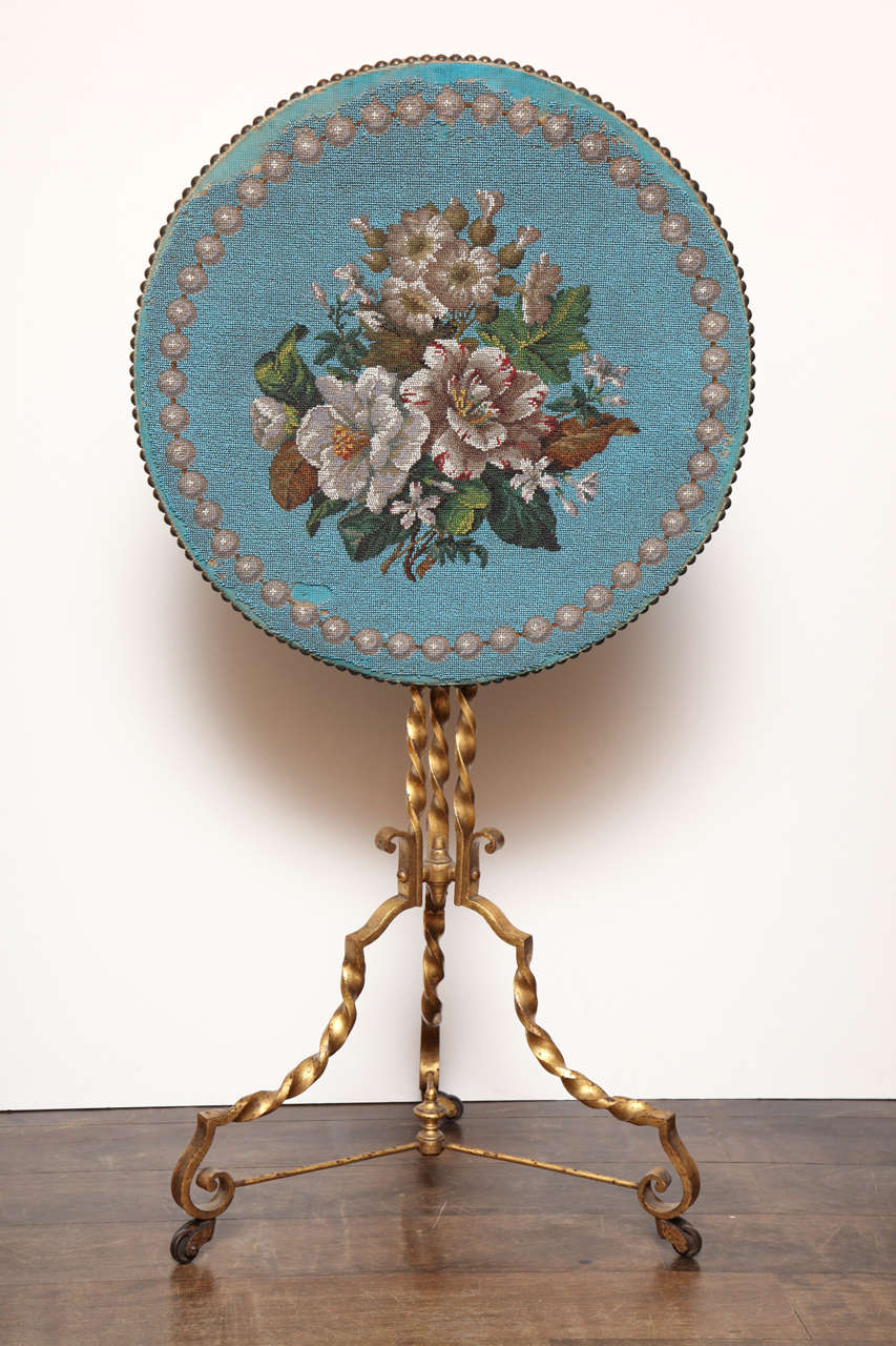 A charming French tilt-top table, made by the Paris firm Maison Heuret, with a glass-beaded top depicting a bouquet of flowers on a gilt wrought iron base. Made in France in the 1860s.