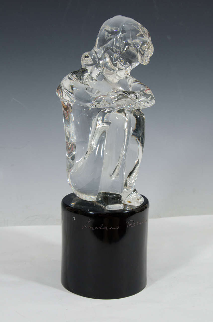 A glass sculpture of a seated girl on a black circular base signed by Loredano Rosin.