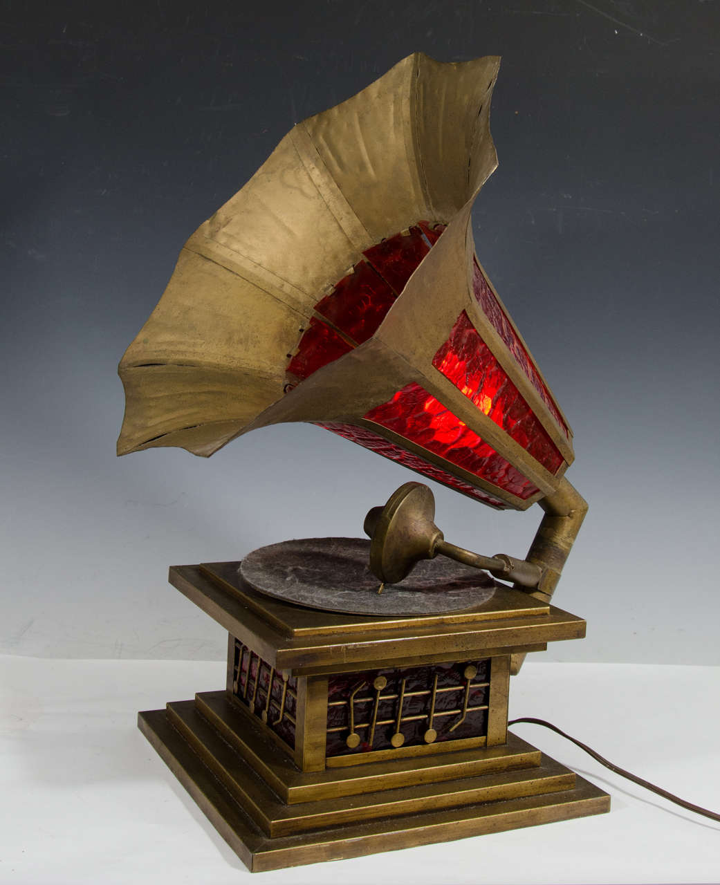 A vintage Victrola hand formed table lamp with red slag glass, circa 1940s. The glass lights internally in the base and speaker.

Good vintage condition with age appropriate wear and patina.