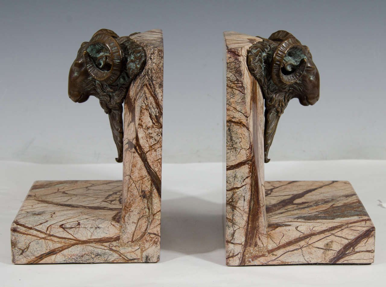 A vintage pair of brown marble and brass bookends embellished with ram's heads. Good condition, consistent with age and wear.