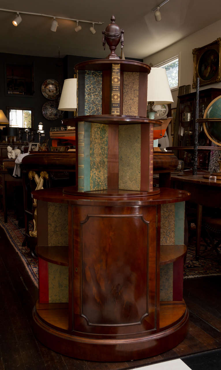 A pair of impressive English Edwardian mahogany revolving bookcase cabinets. Three circular tiers surmounted with a solid carved swag draped urn,
finial. The bottom cabinet having two doors and four divided book shelves. The second a revolving tier