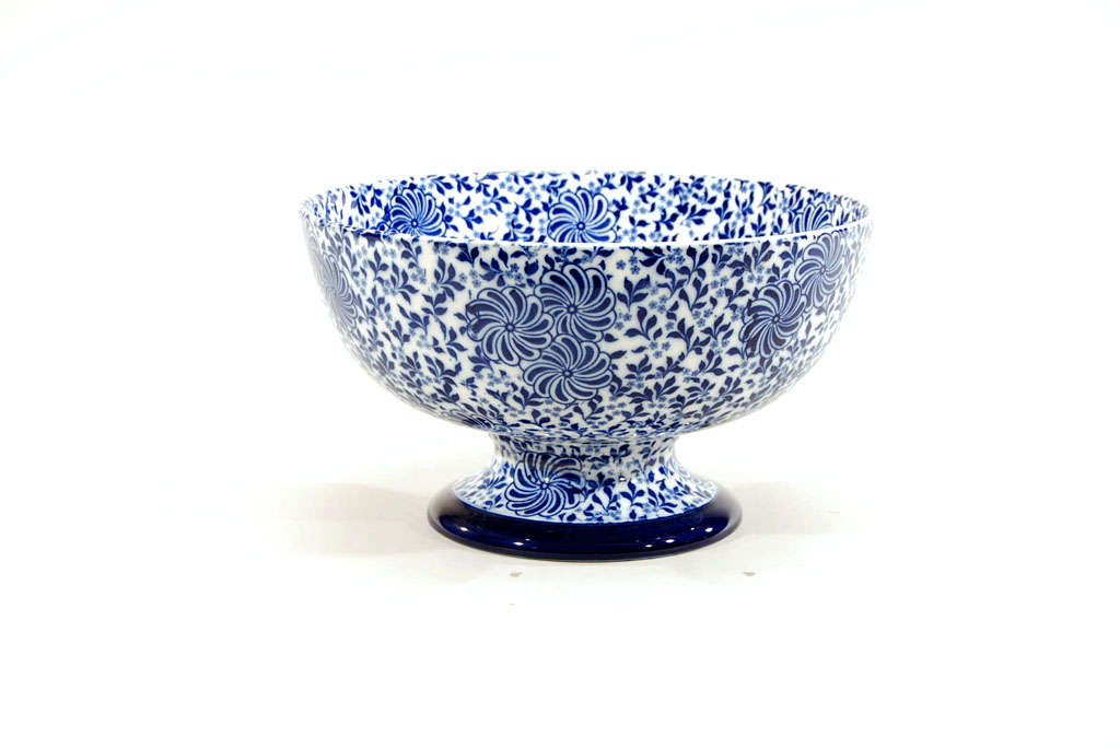 This Doulton Burslem footed punchbowl is decorated inside and out with a masterful transfer of two colors of cobalt blue in an Aesthetic Movement pattern which is both graphic and fanciful. The foot rim is decorated with a rich cobalt blue enamel