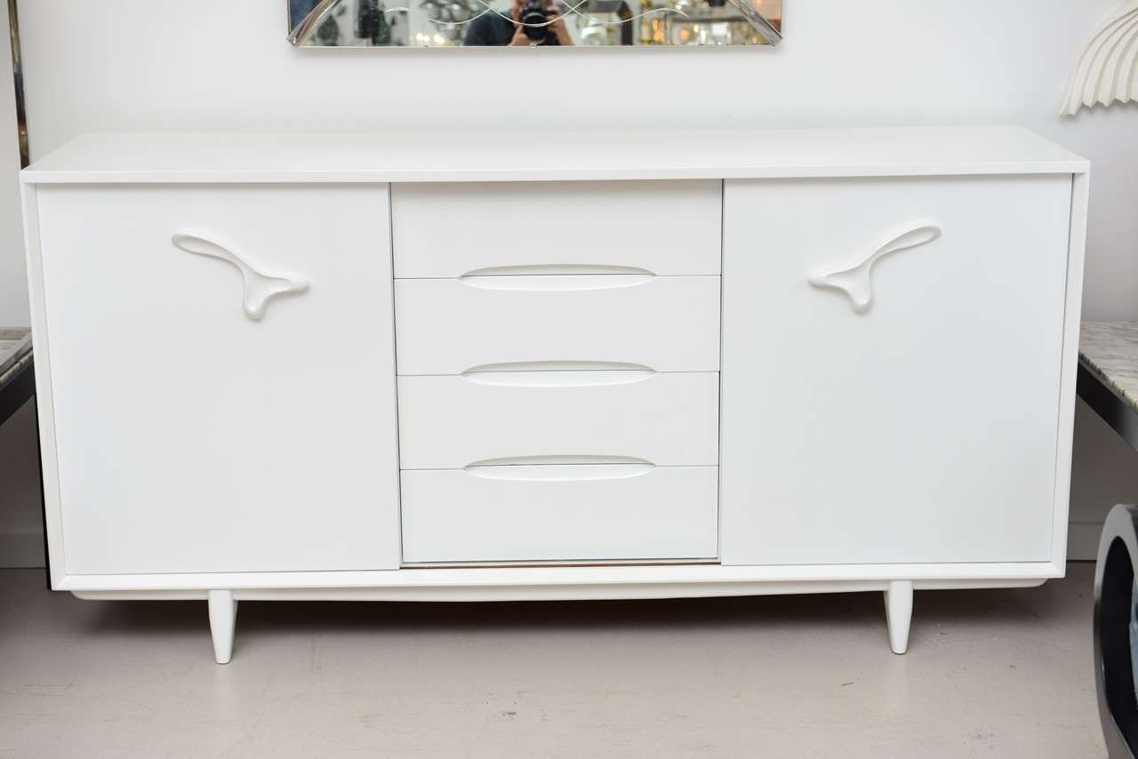 Vintage Mid Century modern credenza by designer Paul Laszlo.
The cabinet has been professionally restored in white. The front doors slide to reveal drawers and storage.