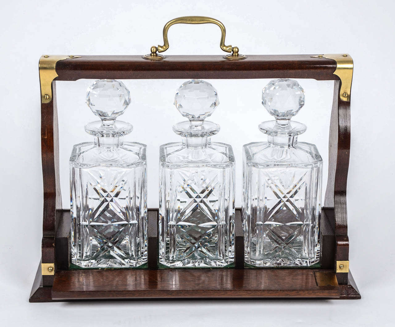 This TANTALUS holds three matching heavily cut, Crystal (Cut Glass), square based, straight sided spirit decanters, all with original faceted ball stoppers.

The decanters sit in a quality mahogany framed box with brass corner mounts and a solid