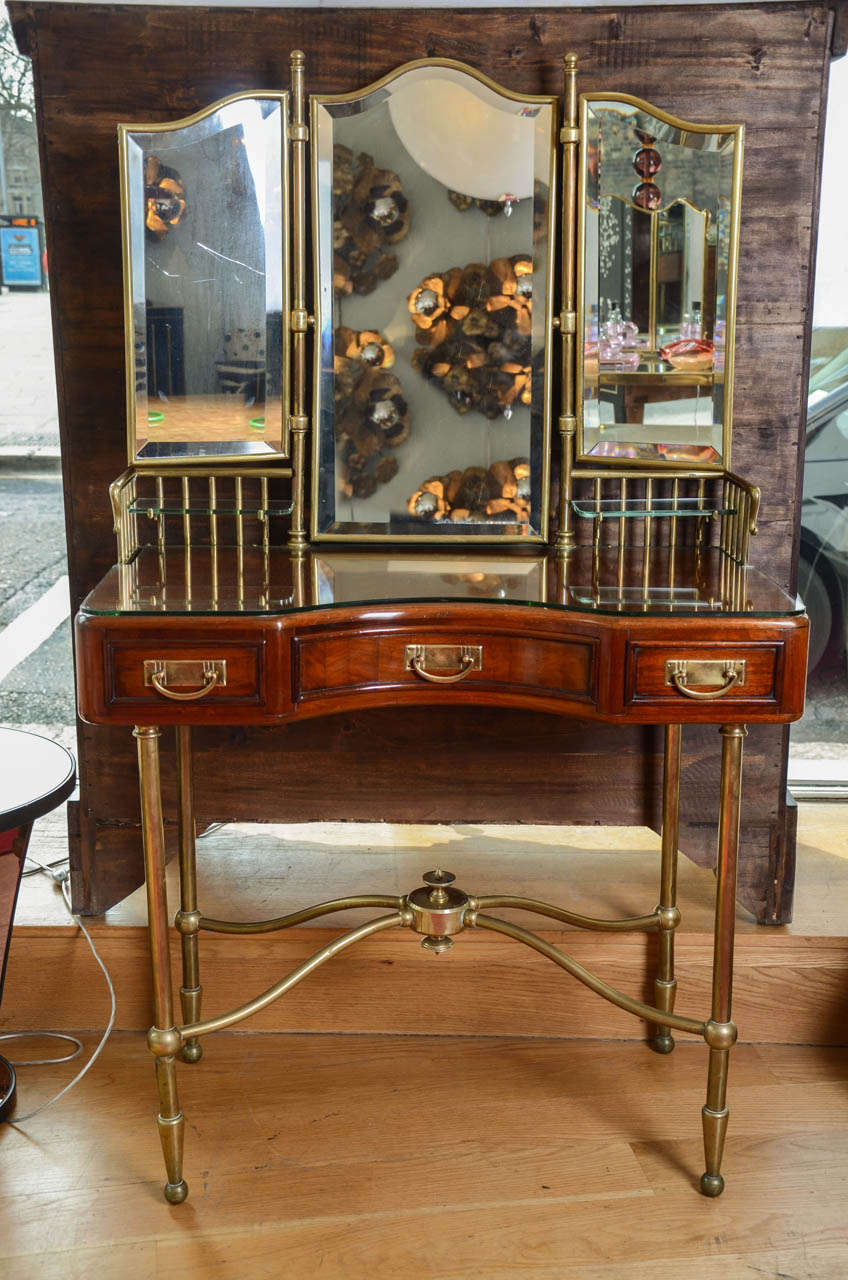 Edwardian French vanity table in Mahogany with brass legs and with original raised brass sides holding two glass shelves attached to triple bevelled mirror, also in brass