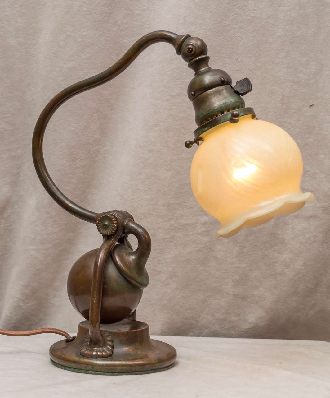 In simple terms what we have here is a wonderful Tiffany counter balance bronze base with a period, handblown unsigned shade. This particular base is one of Tiffanies most sought after model. The counter balance ball actually swings through those