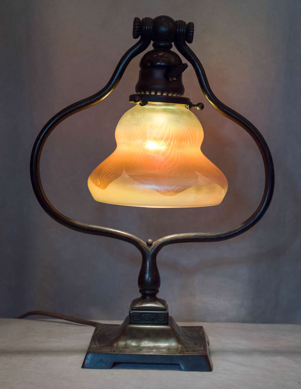 This very attractive Tiffany Studios lamp is a nice example of their harp style table lamp. The shade position can be adjusted with the shade moving up or down through the harp. The shade and base are both properly signed. The shade design is what